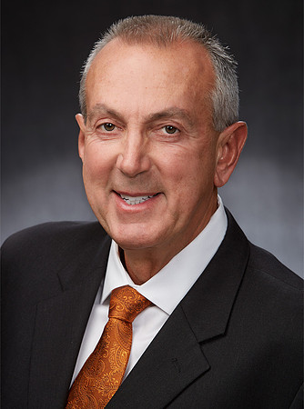 Professional headshot of business man in front of a neutral background