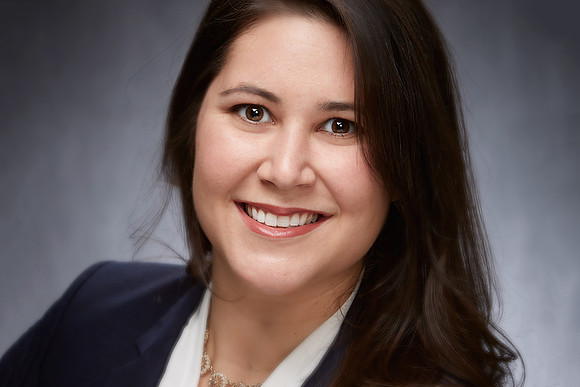 Business headshot of woman smiling into camera on a grey background