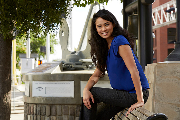 Pretty girl sitting on a bench smiling at the camera for a professional portrait