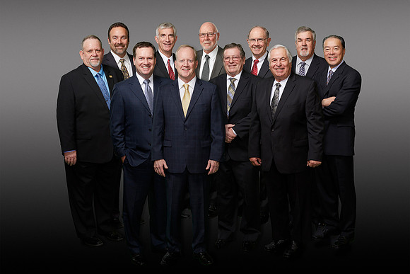 Group portrait of 11 professional executives on a grey gradient background/