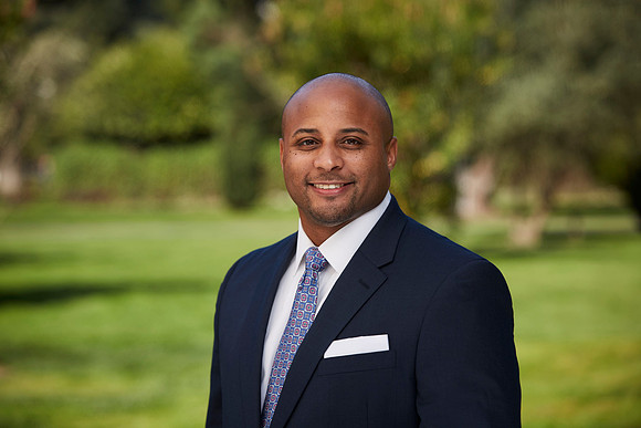 Business headshot of a male executive in a nice suit in the park smiling at the camera.
